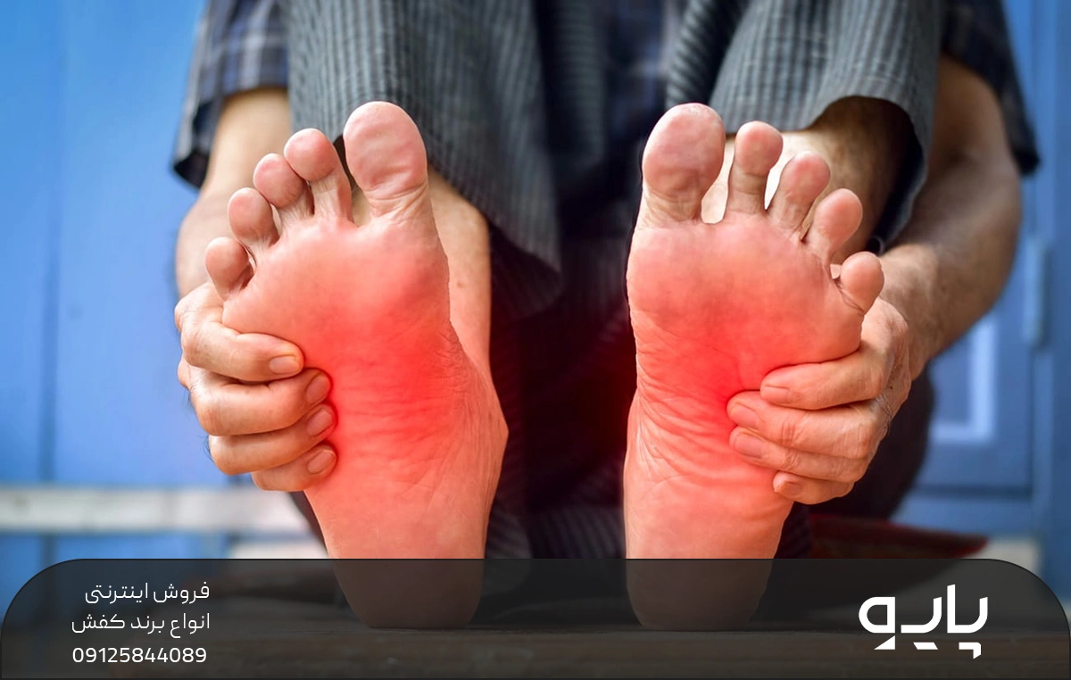 پاهای فردی که کف آن ها قرمز شده و درد می کند و فرد با دست کف پاها را ماساژ می دهد