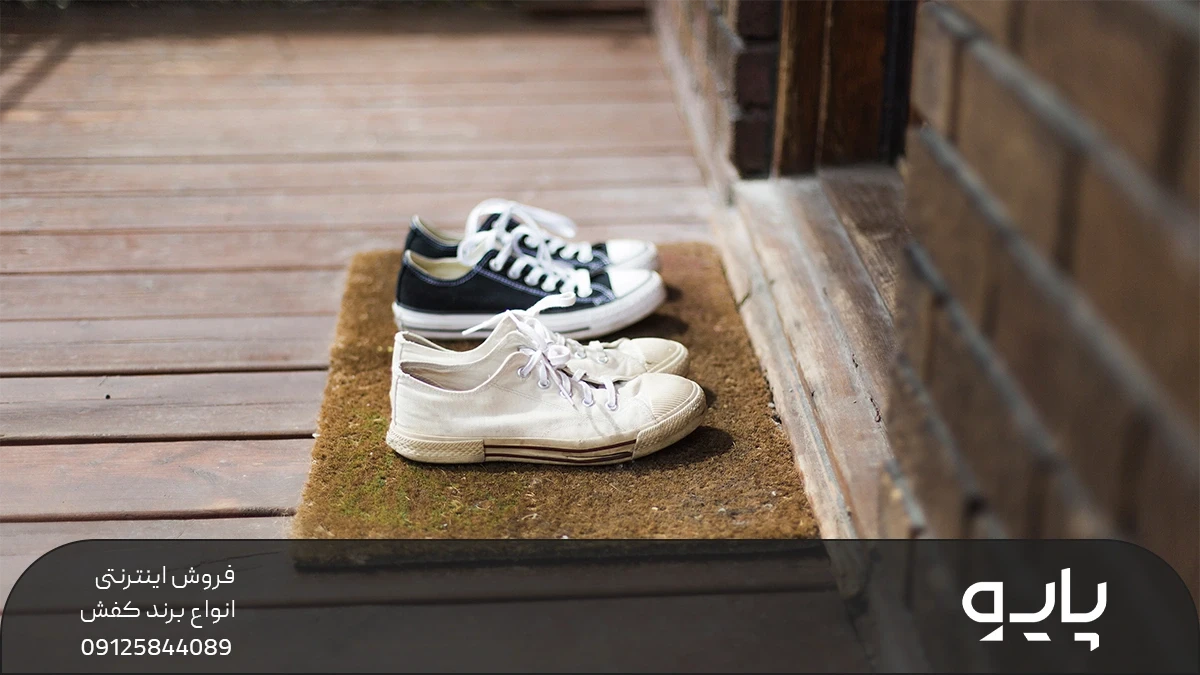 2 جفت کفش که روی پادری بیرون از خانه قرار گرفته است