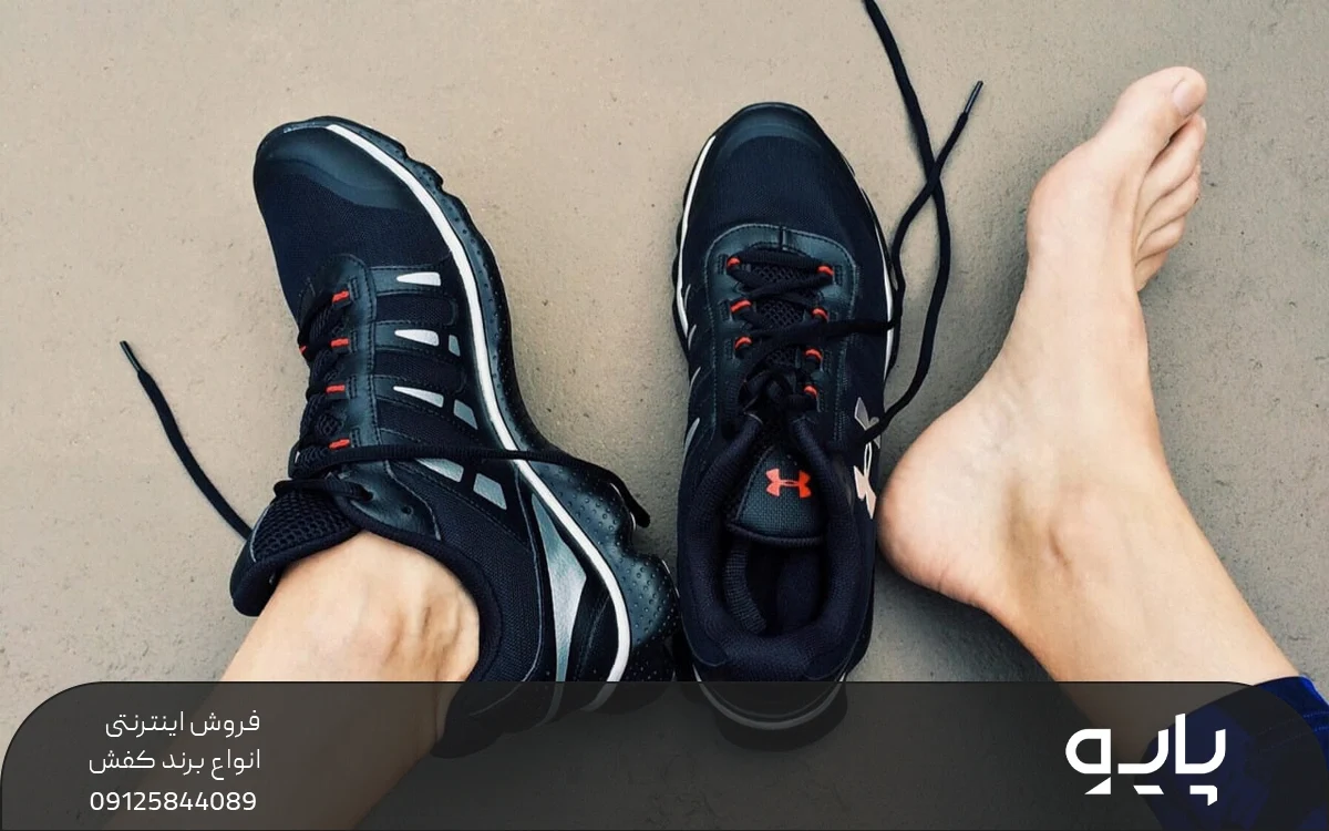 یک جفت کفش ورزشی مشکی که یک لنگه آن در پای فرد است و لنگه دیگر روی زمین